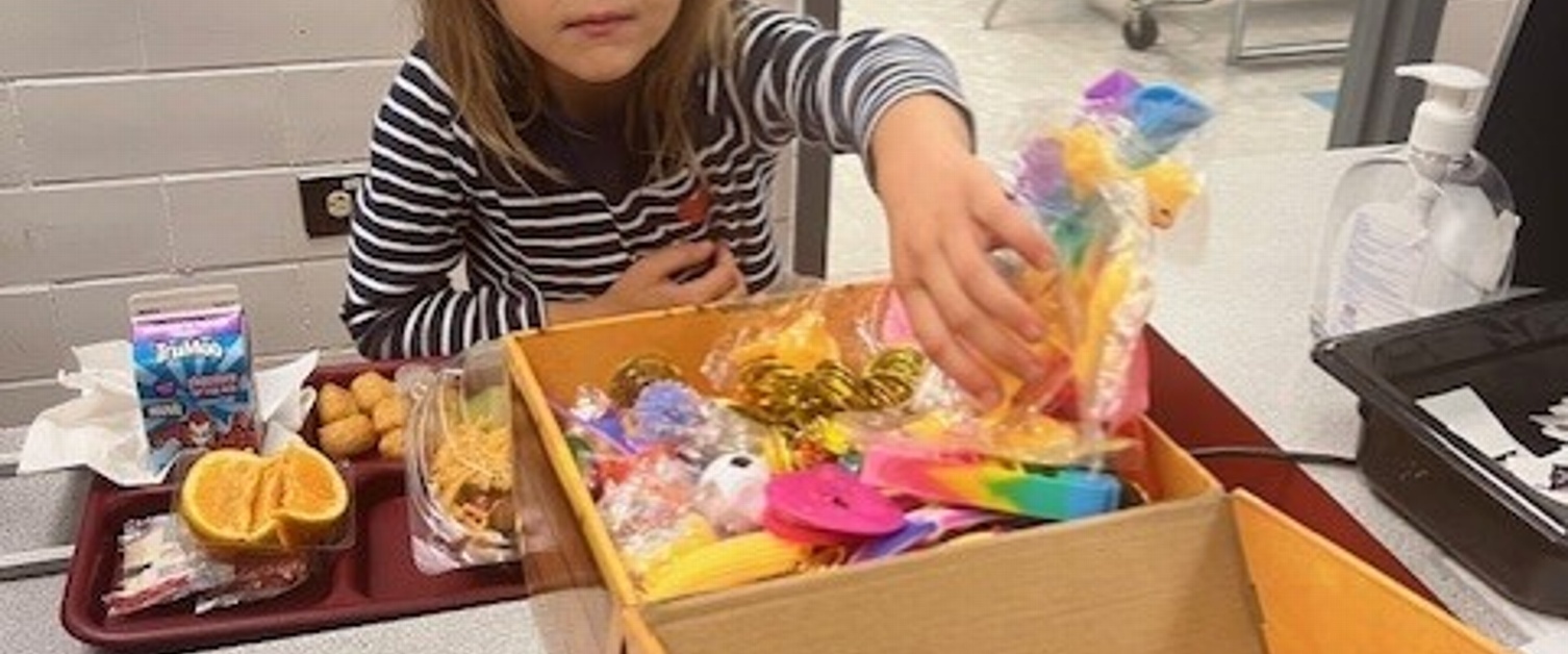 A young student picking a Halloween treat from a treasure chest for lunch